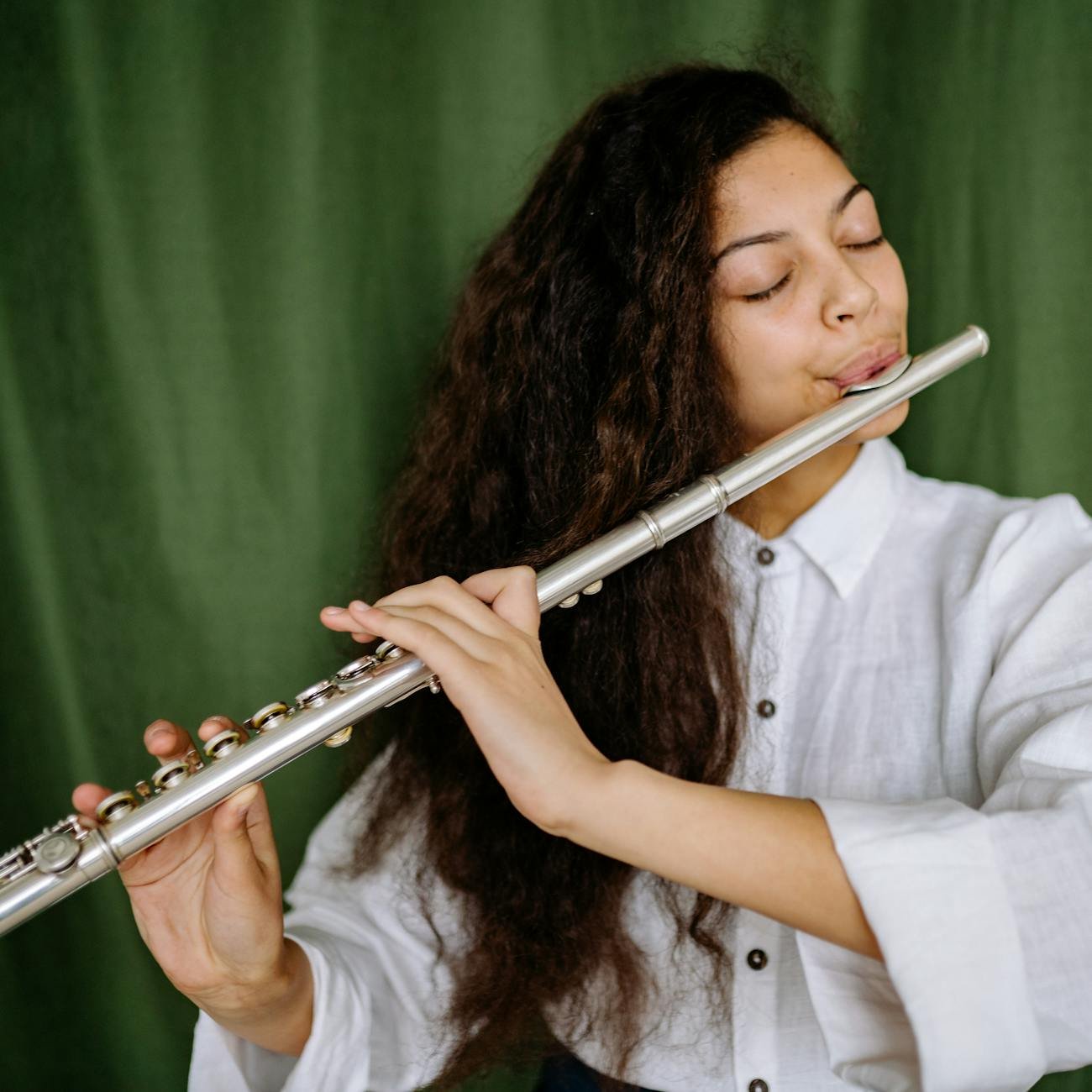 woman in white long sleeve shirt playing flute