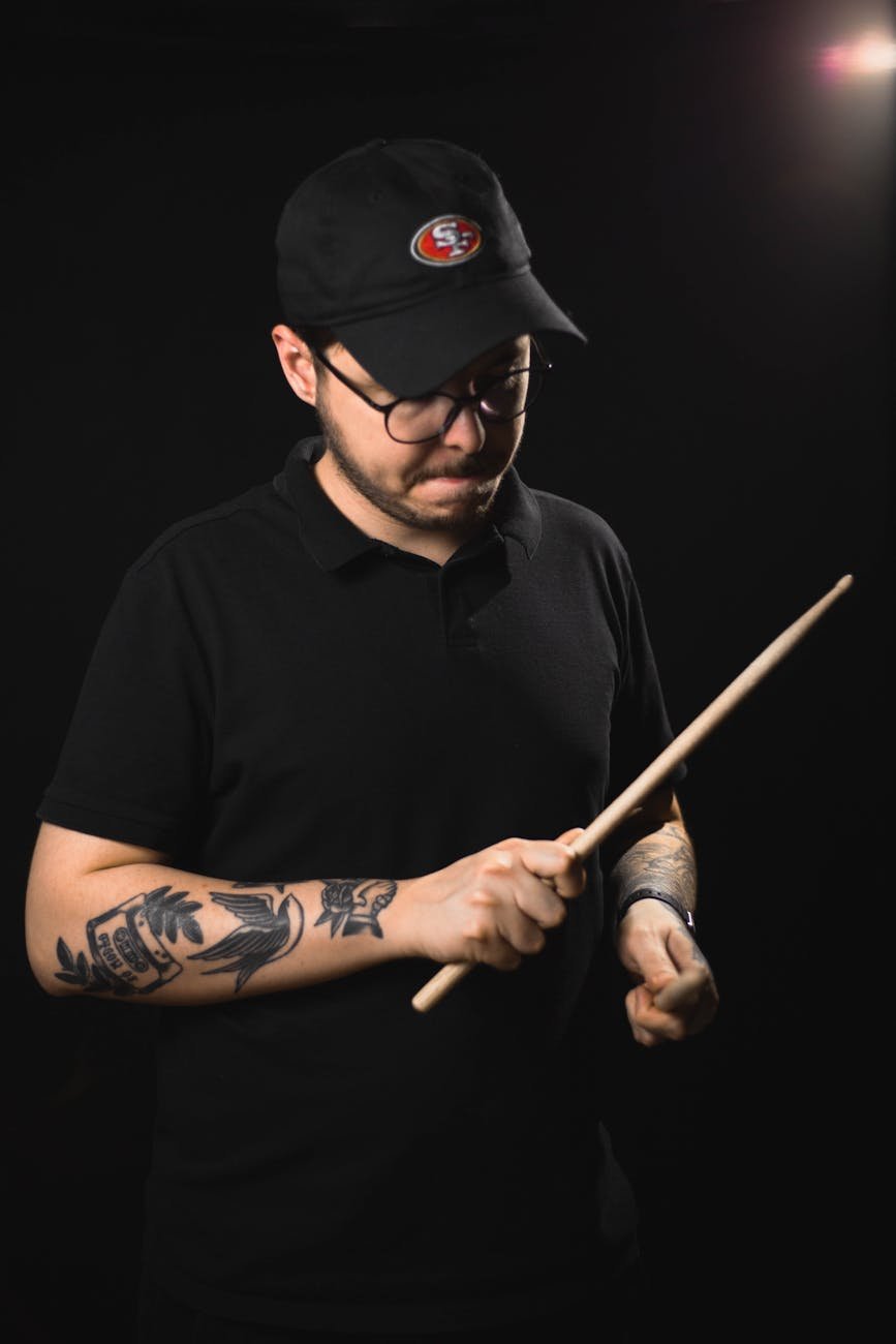 man in black polo shirt holding drumsticks